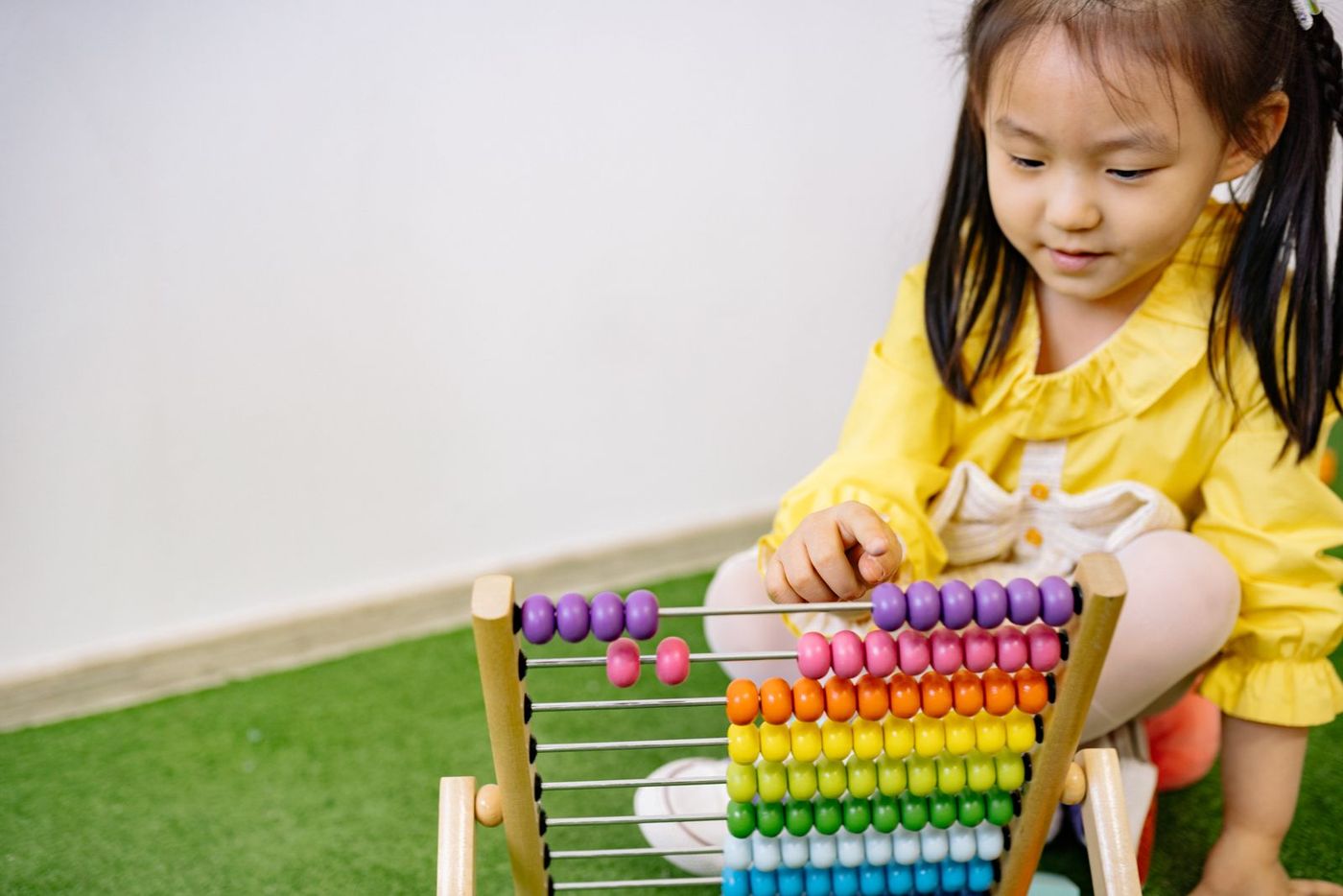 A preschooler counting colourful beads