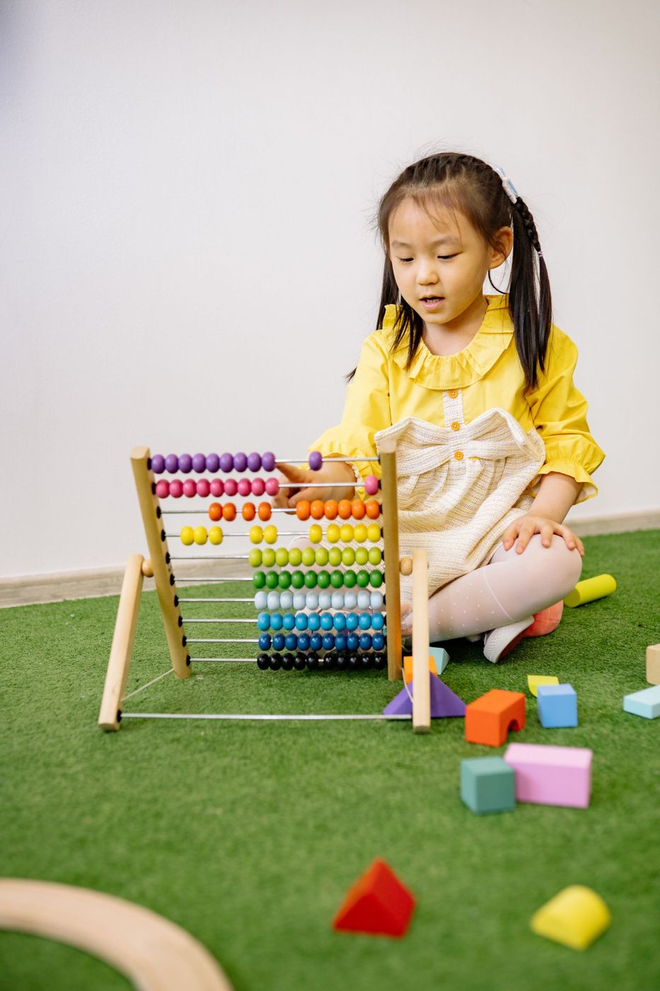 A preschooler counting beads and blocks during a math game